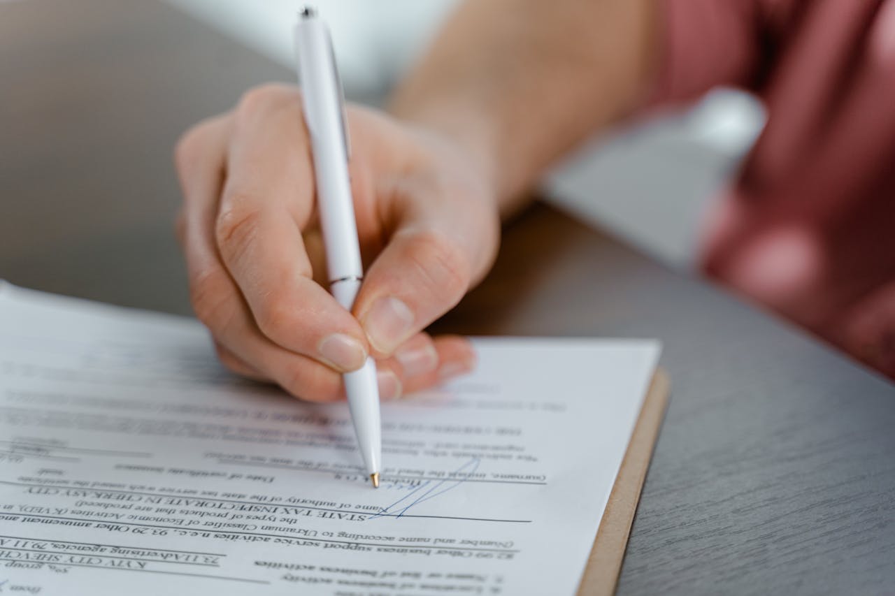 Mastering the First Impression: Your intriguing post title goes here Detailed view of a hand writing a signature on an official document with a ballpoint pen.